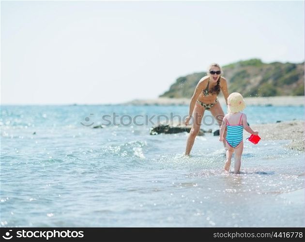 Happy mother and baby girl playing at seaside