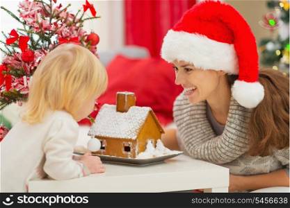 Happy mother and baby looking on Christmas Gingerbread House
