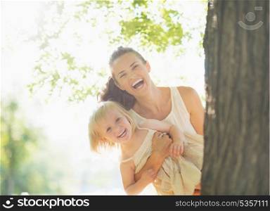 Happy mother and baby looking out from tree