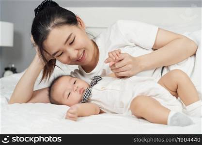 happy mother and baby lying on a bed at home