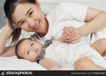 happy mother and baby lying on a bed at home