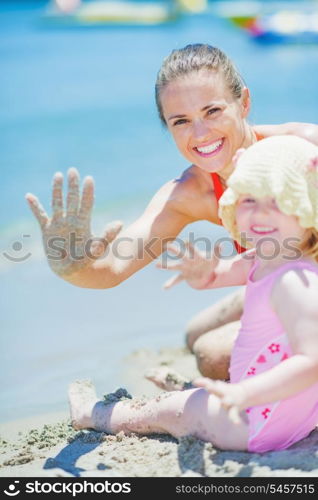 Happy mother and baby on beach greeting