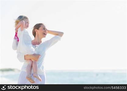 Happy mother and baby on beach looking into distance