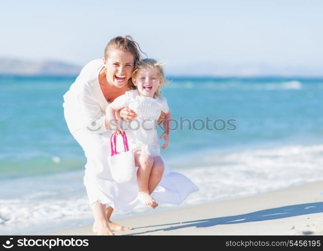 Happy mother and baby on sea shore having fun