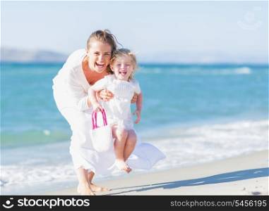Happy mother and baby on sea shore having fun