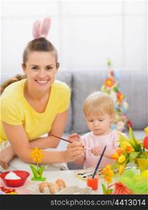 Happy mother and baby painting on Easter eggs