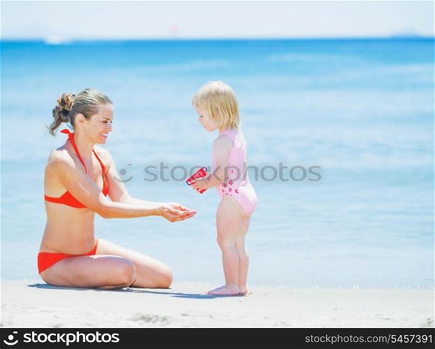 Happy mother and baby playing on beach