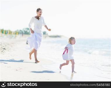 Happy mother and baby playing on sea coast