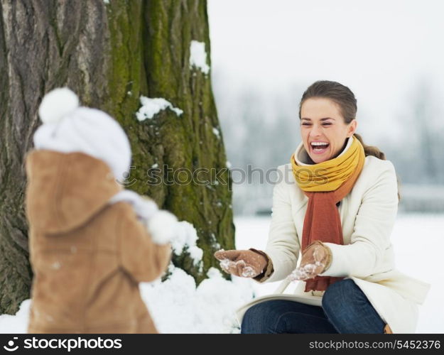 Happy mother and baby playing outdoors in winter