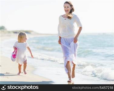 Happy mother and baby running on sea shore