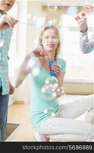 Happy mother and children playing with bubble wands at home