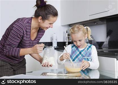 Happy mother and daughter baking together in kitchen
