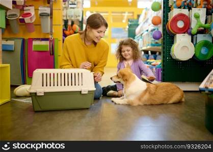Happy mother and daughter choosing new carrier for their corgi dog at pet shop. Happy family shopping. Happy mother and daughter choosing new carrier for their corgi dog at pet shop