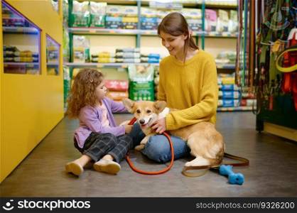 Happy mother and daughter choosing new leash for their corgi dog. Buying accessory for domestic animal at pet shop. Happy mother and daughter choosing new leash for their corgi dog
