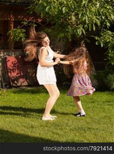 Happy mother and daughter dancing on grass at sunny day