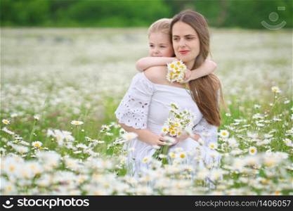 Happy mother and daughter in big camomile mountain meadow. Emotional, love and care scene.