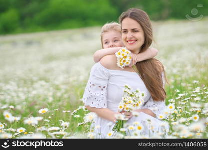 Happy mother and daughter in big camomile mountain meadow. Emotional, love and care scene.