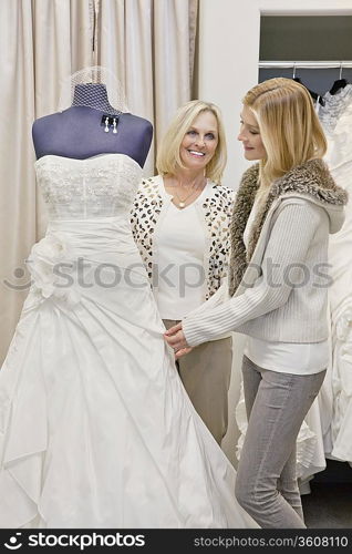 Happy mother and daughter looking at beautiful wedding dress in bridal store