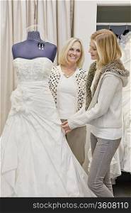 Happy mother and daughter looking at beautiful wedding dress in bridal store