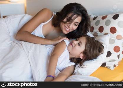 Happy mother and daughter lying on bed