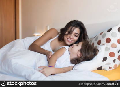 Happy mother and daughter lying on bed