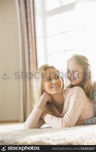 Happy mother and daughter lying on floor at home