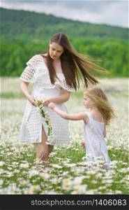 Happy mother and daughter making wreath in big camomile mountain meadow. Emotional, love and care scene.