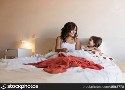 Happy mother and daughter relaxing on bed