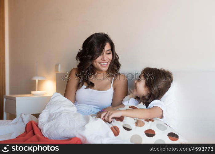 Happy mother and daughter relaxing on bed