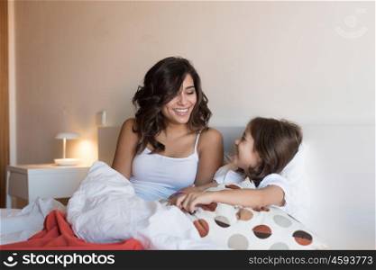 Happy mother and daughter relaxing on bed