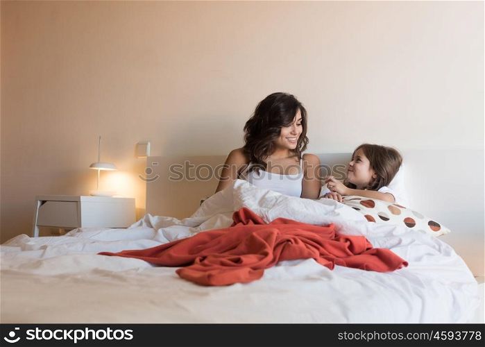 Happy mother and daughter relaxing on bed