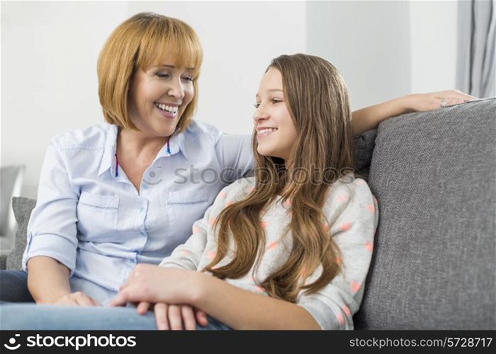 Happy mother and daughter relaxing on sofa at home