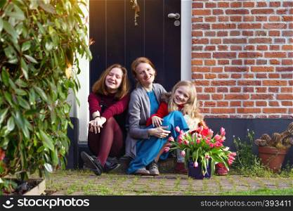 happy mother and daughters sit on the porch of their house
