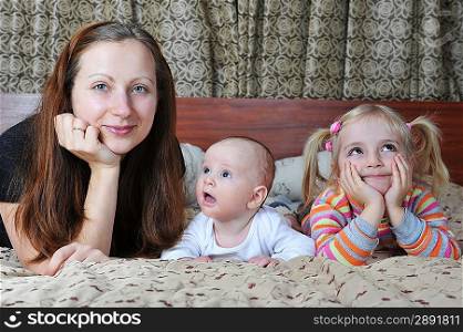 Happy mother and her children lying on bed