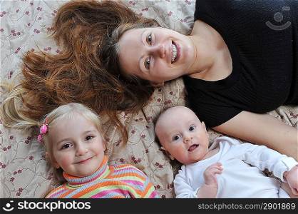 Happy mother and her children lying on bed