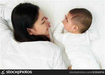 happy mother and infant baby lying on a bed