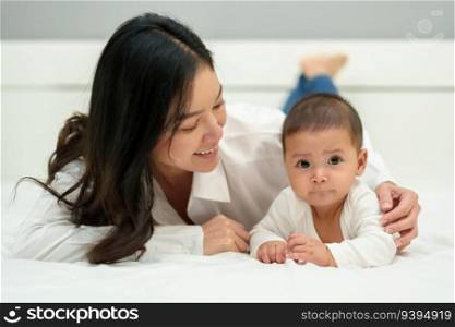 happy mother and infant baby lying prone on a bed