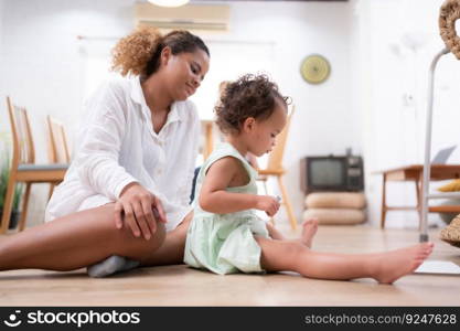 happy mother and little daughter sitting on floor at home