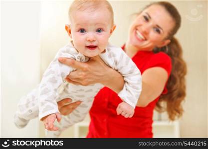 Happy mother and lovely baby playing on divan