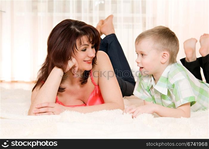 happy mother and son lie on the carpet