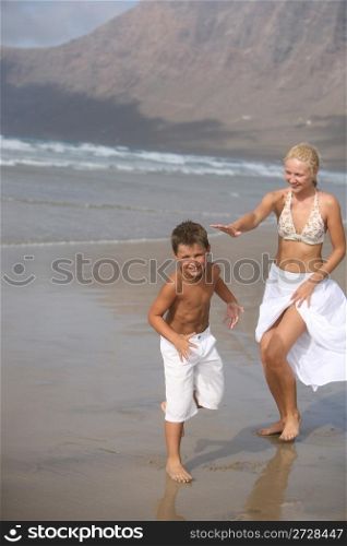 Happy Mother and son play on the beach