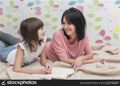 happy mother daughter drawing lying bed