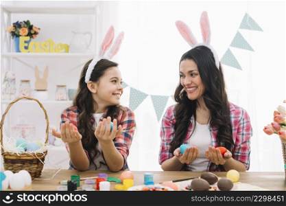 happy mother daughter holding easter eggs hand looking each other home