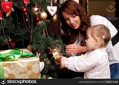 Happy mother decorating christmas tree with her baby