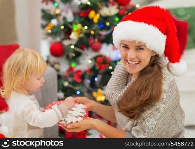 Happy mother giving baby Christmas cookies