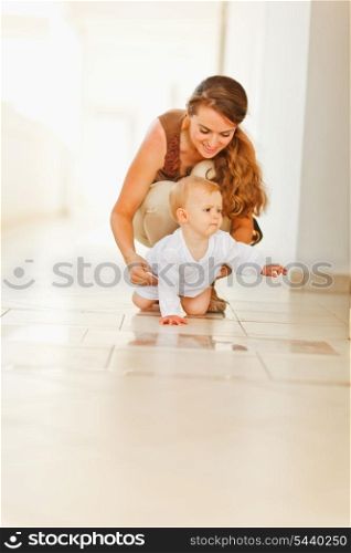 Happy mother helping baby to creep