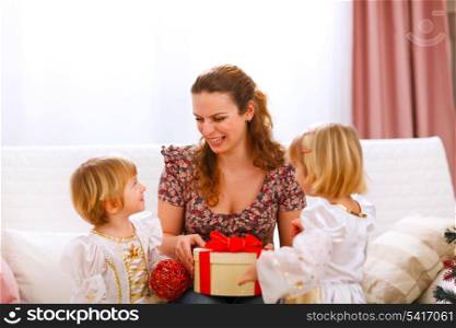 Happy mother holding gift of her twins daughters&#xA;