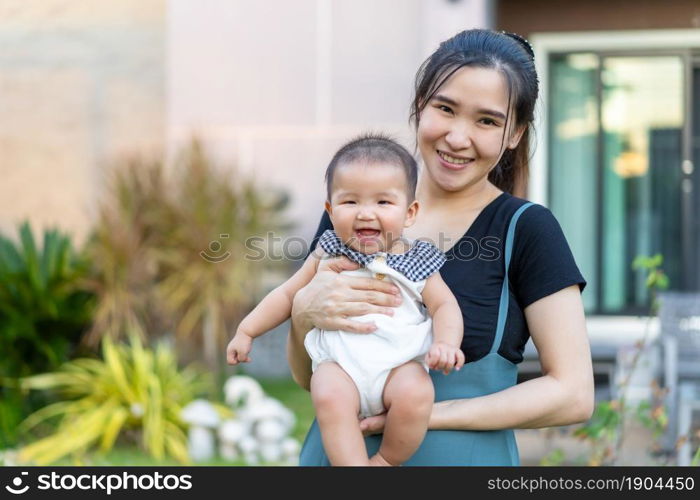 happy mother holding newborn baby in a tender embrace outside her house