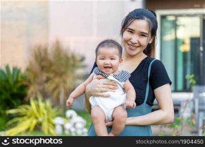 happy mother holding newborn baby in a tender embrace outside her house