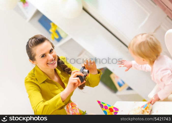 Happy mother making photos of celebrating first birthday baby